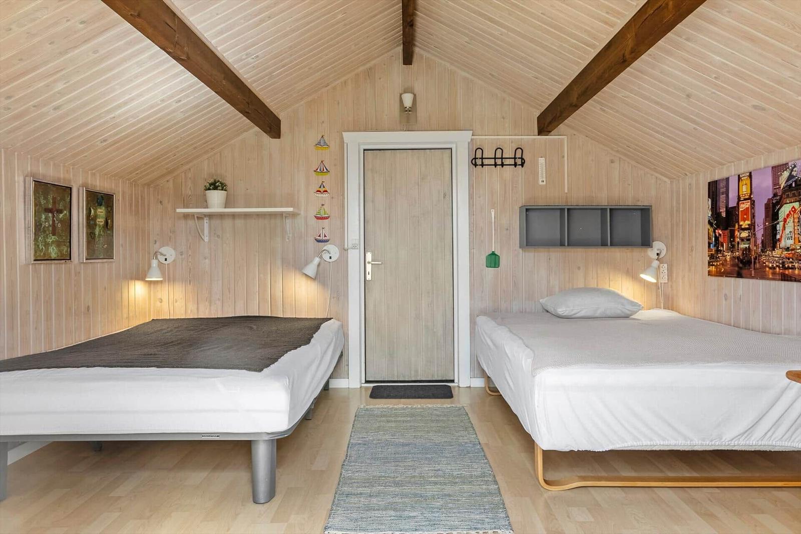Zwei Betten in einem holzverkleideten Raum mit Dachschräge und Wandbildern.