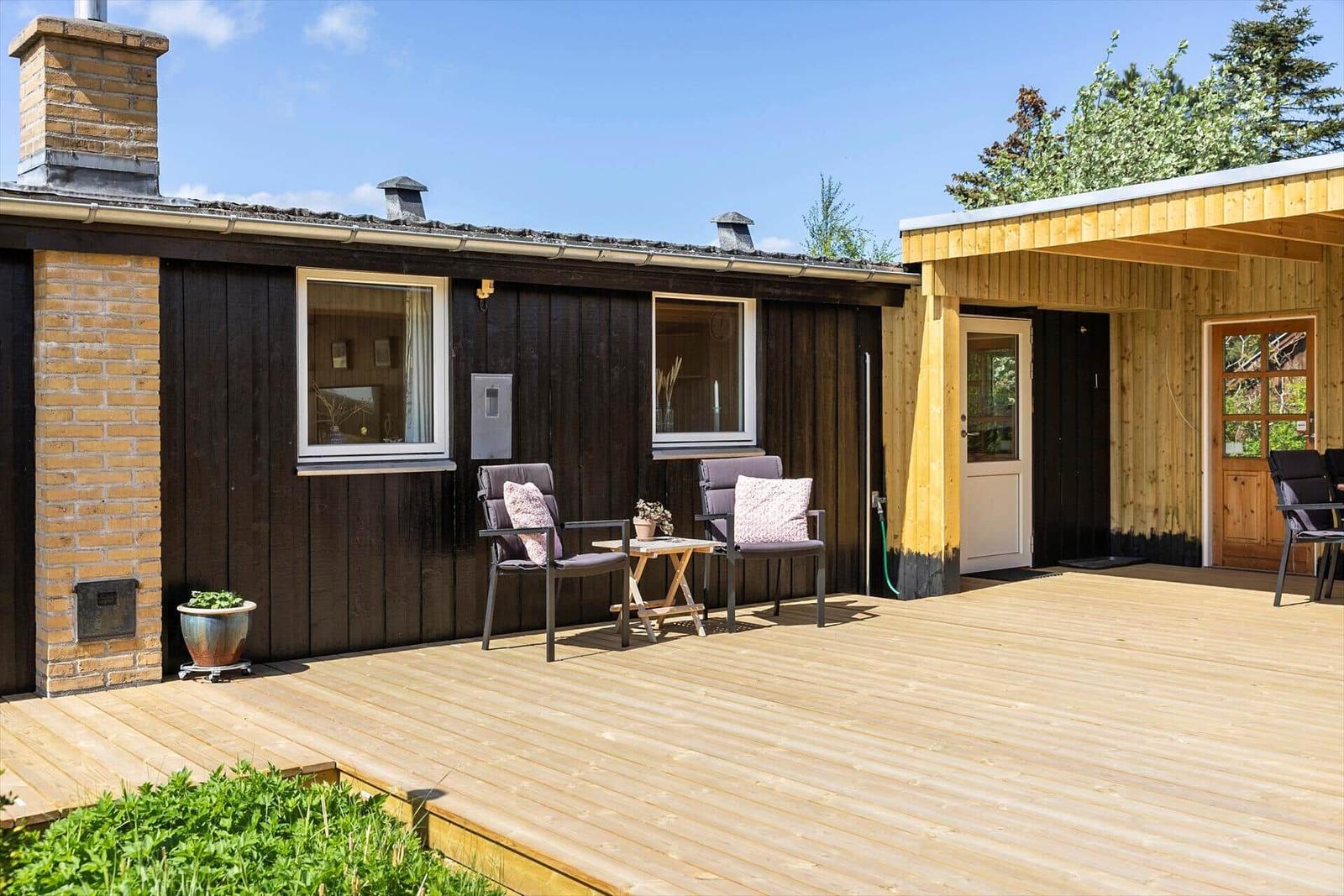 Holzterrasse mit Sitzgelegenheit und Blick auf das Haus