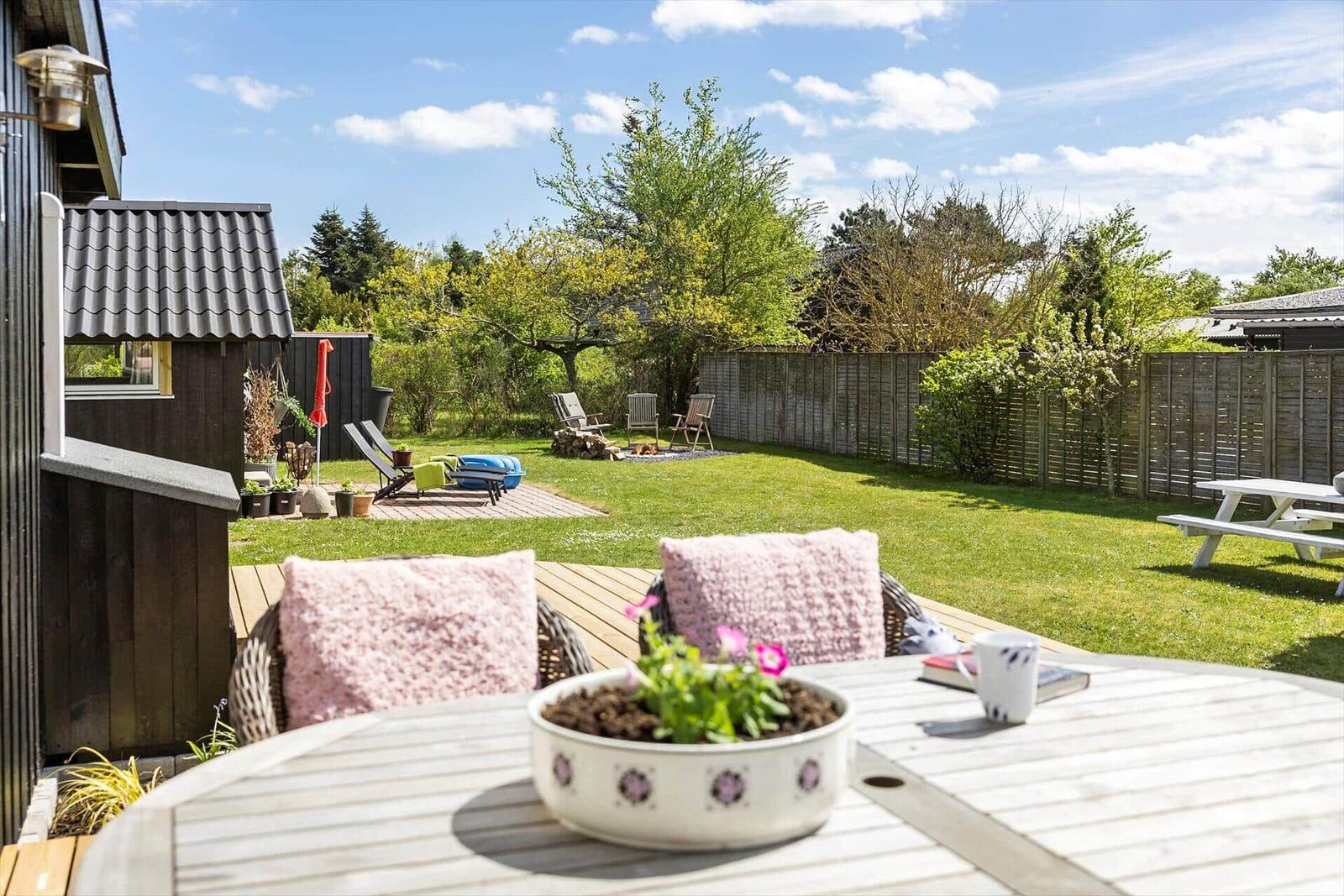 Terrasse mit Tisch, Stühlen und Blick auf den Garten.