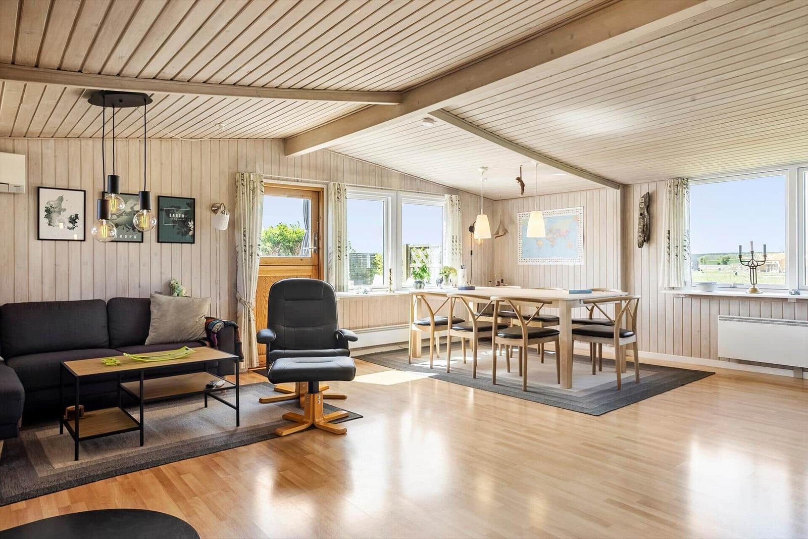 Wohn- und Essbereich mit Holzdielen, Sofa, Stuhl und Tisch.