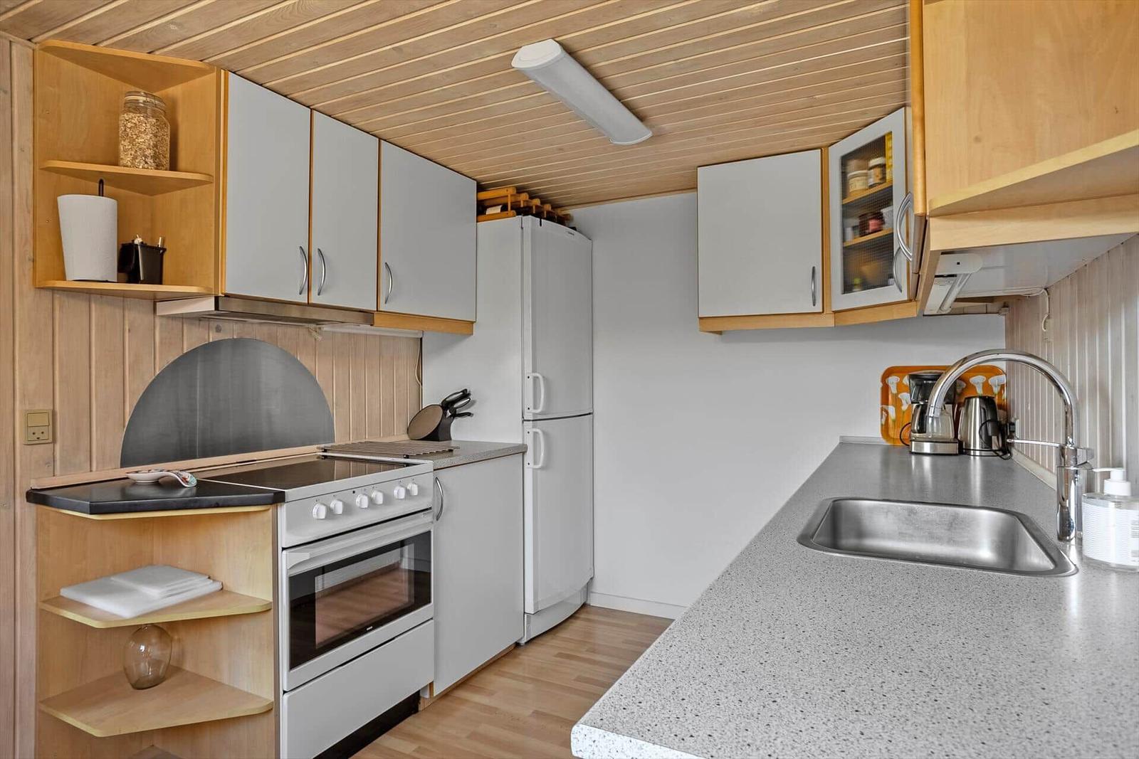 Küche mit Arbeitsplatte, Spüle, Kühlschrank und Herd.