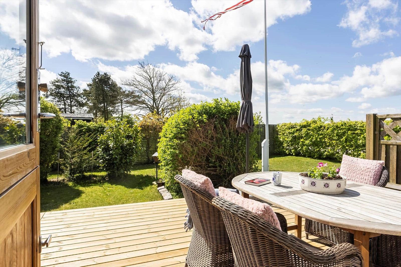 Terrasse mit Tisch, Stühlen und Blick auf den Garten.