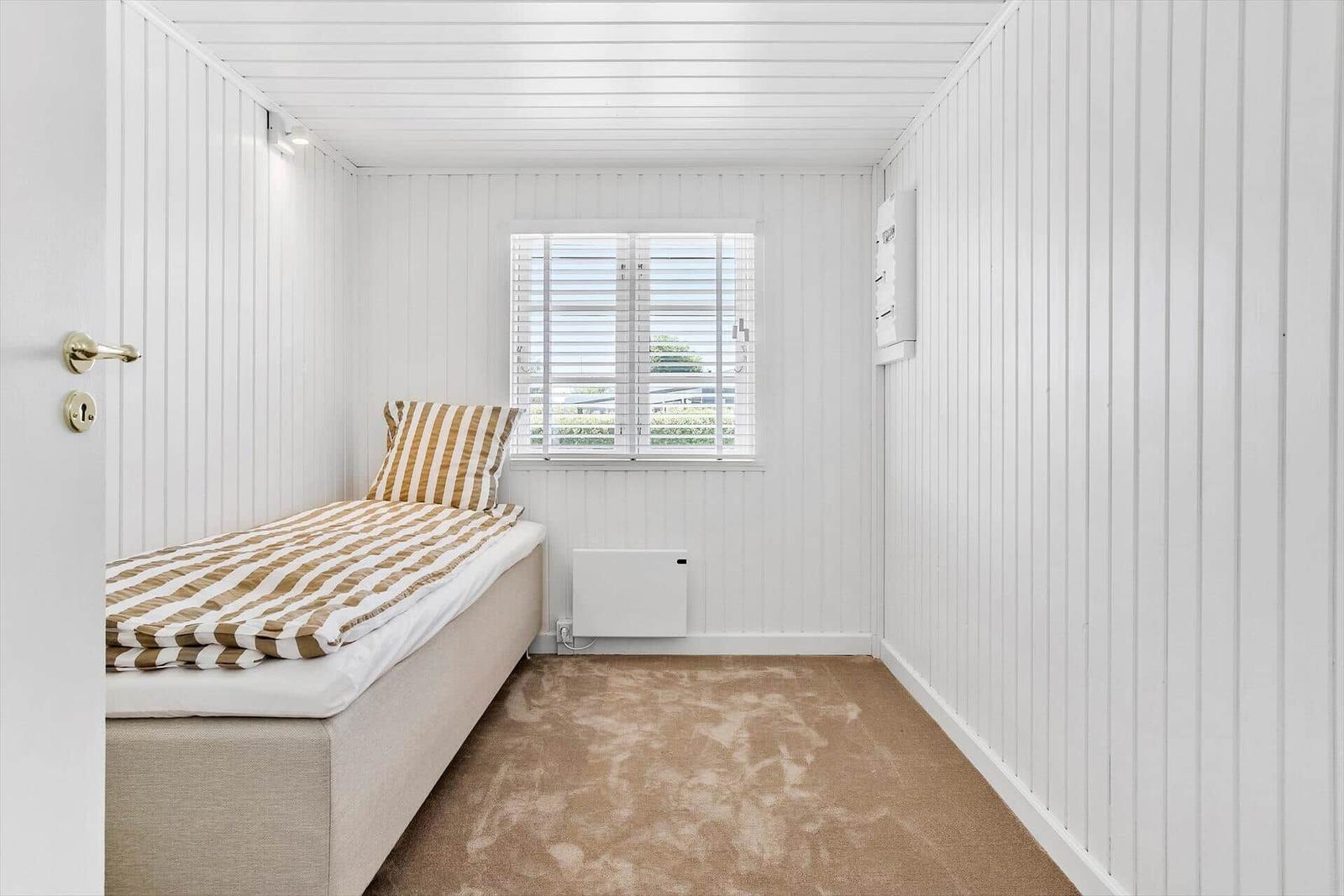 Schlafzimmer mit Bett, Fenster und Heizung.