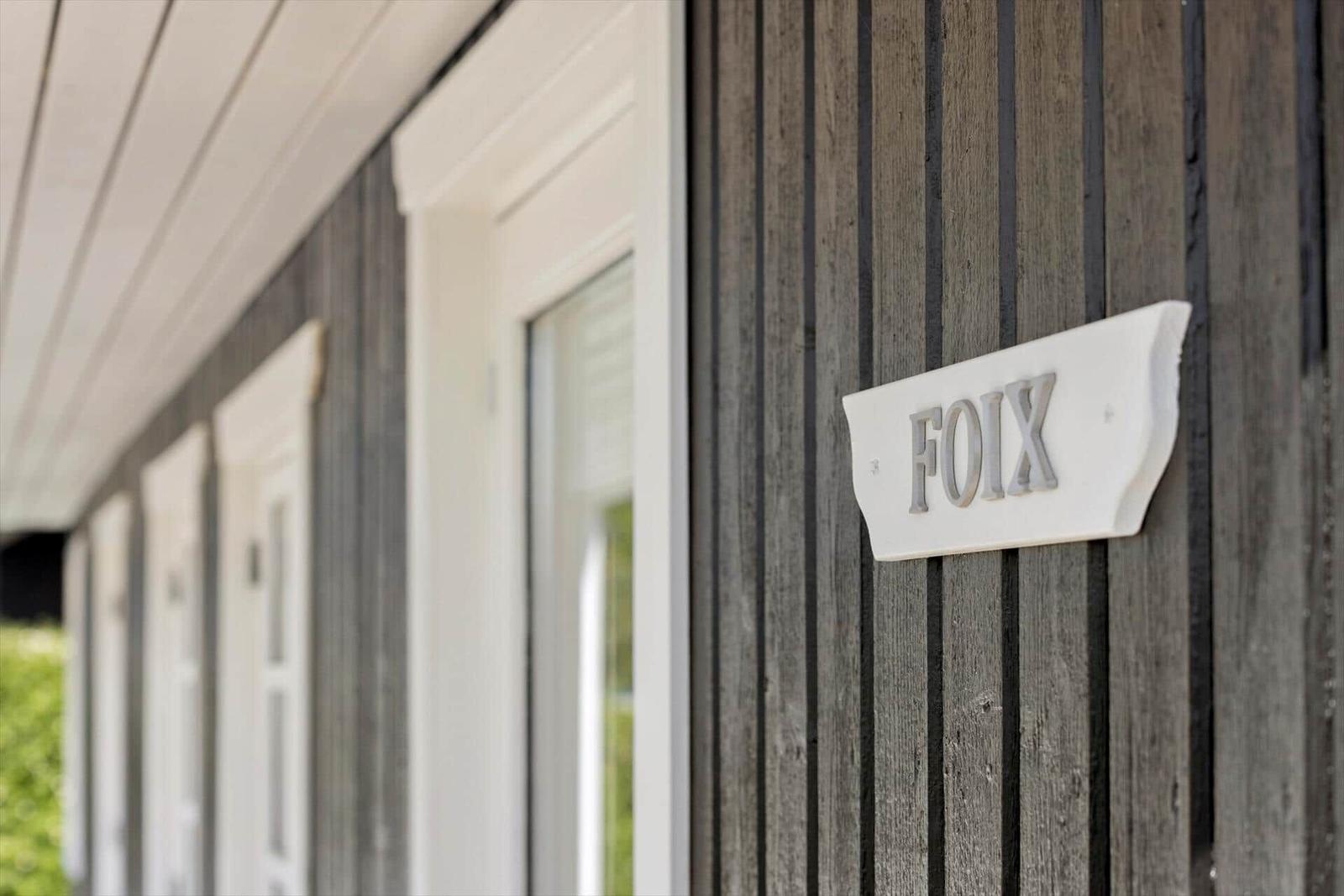 Haus mit Holzfassade und Schild FOIX an der Wand