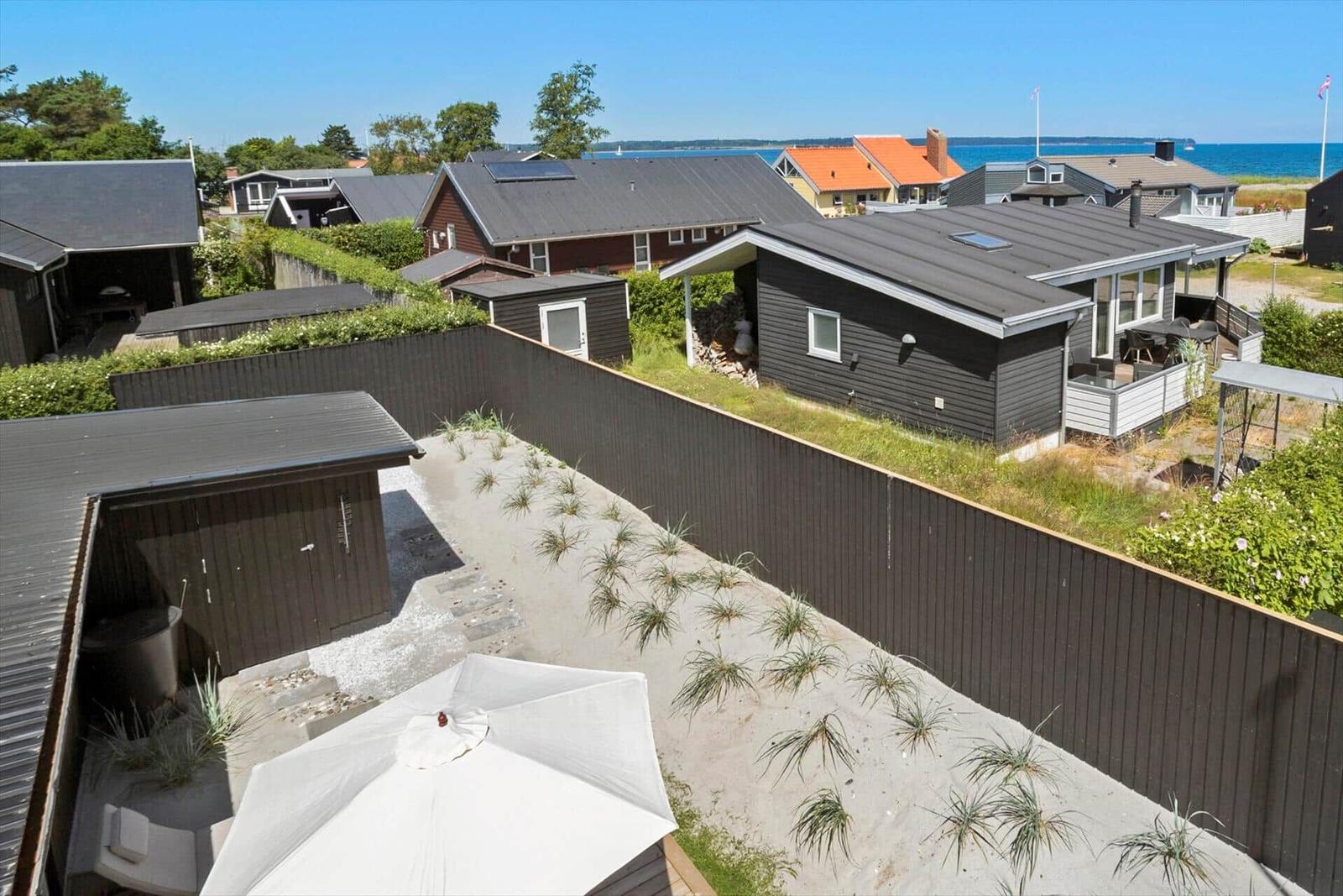 Modernes Ferienhaus mit Terrasse und Garten. Blick auf Meer und Nachbarhäuser.
