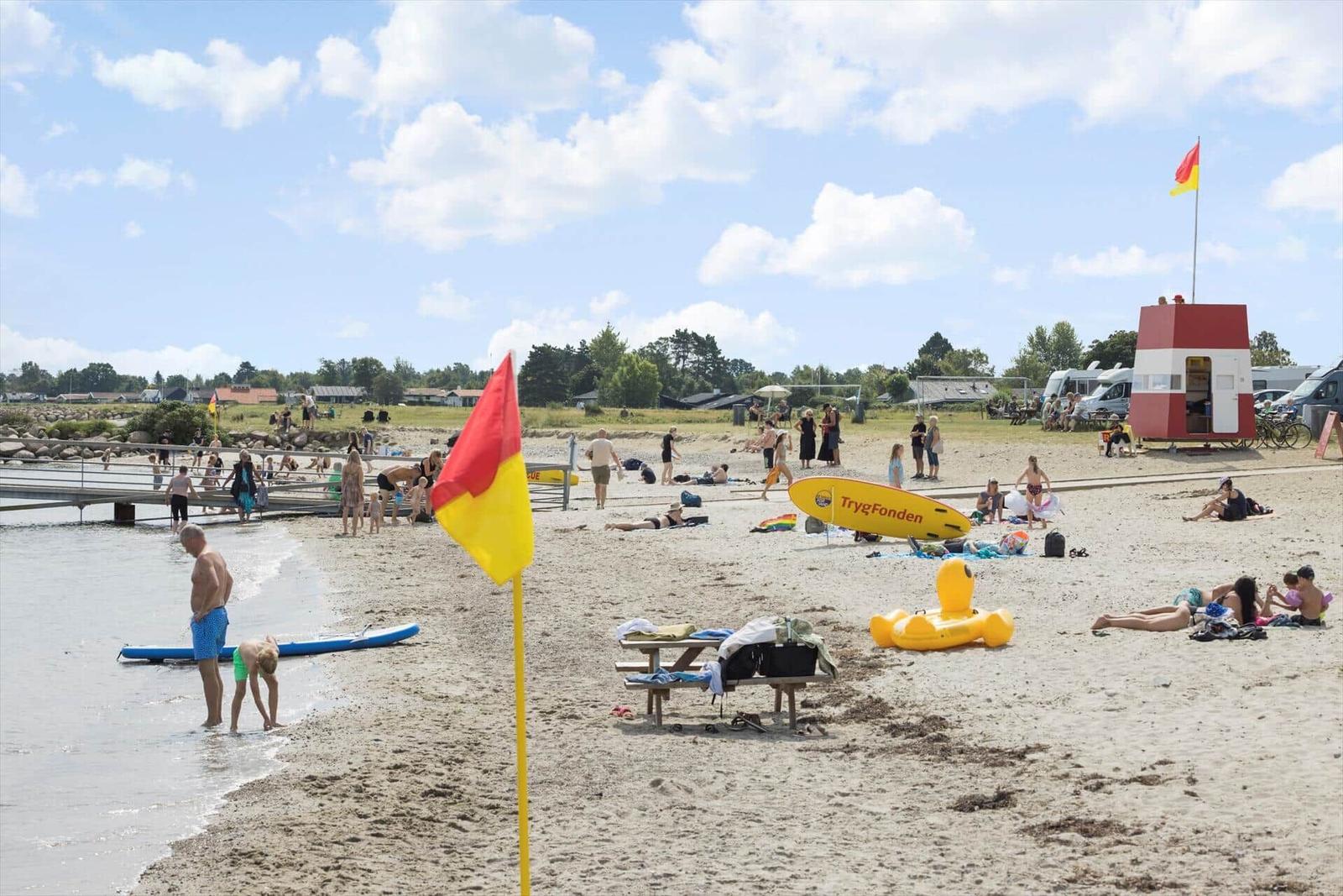 Strand mit Badegästen, Rettungswachtürmchen und Sonnentruhen.