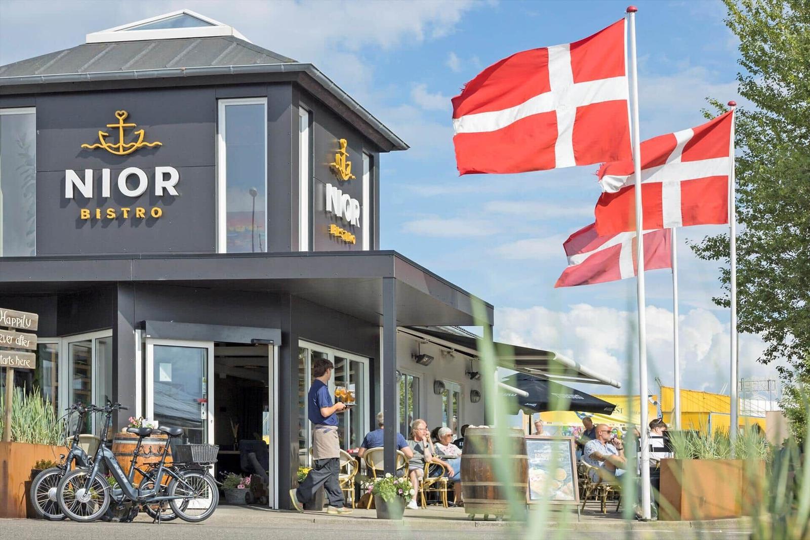 Niord Bistro mit Außenbereich, dänischen Flaggen und Fahrrädern.