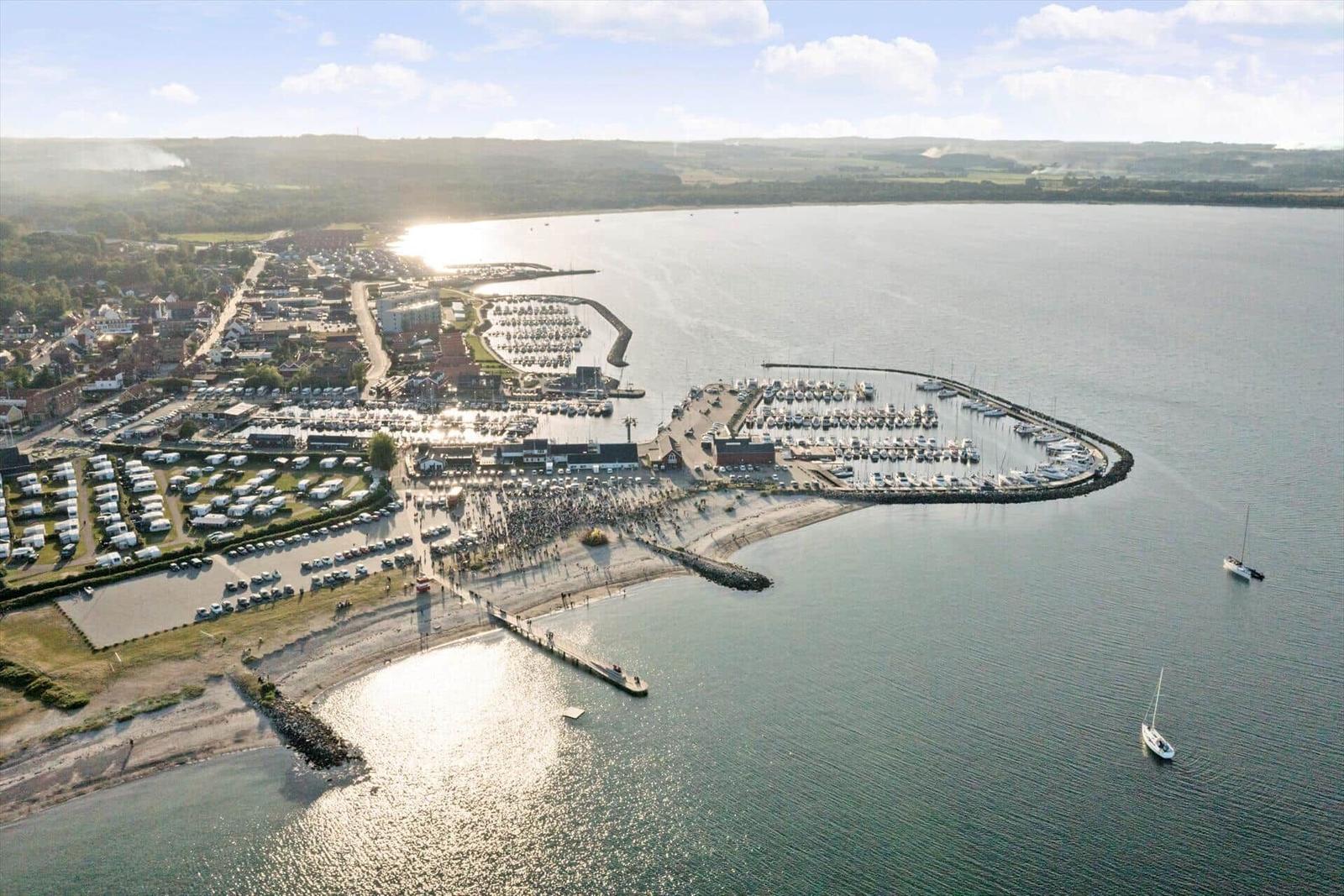 Aerial view of harbor with boats, beach, and surrounding town.