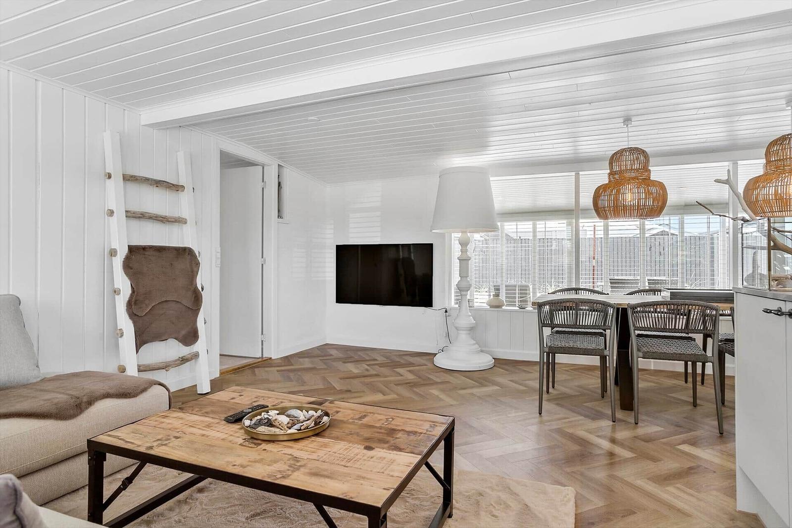 Wohn- und Essbereich mit Holzboden, Fernseher und Esstisch.