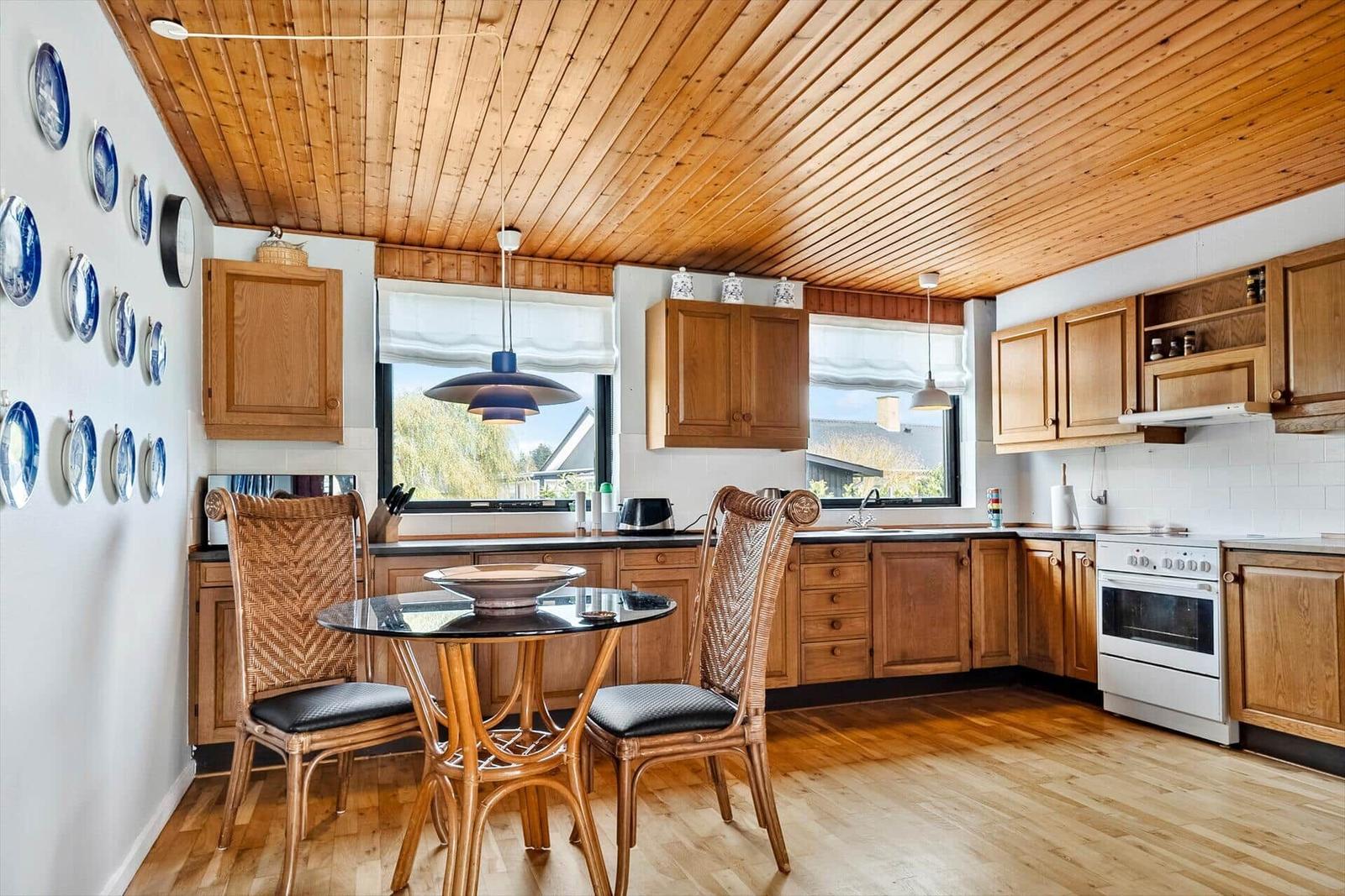 Küche mit Holzdecke, Essbereich und blauen Teller an der Wand.