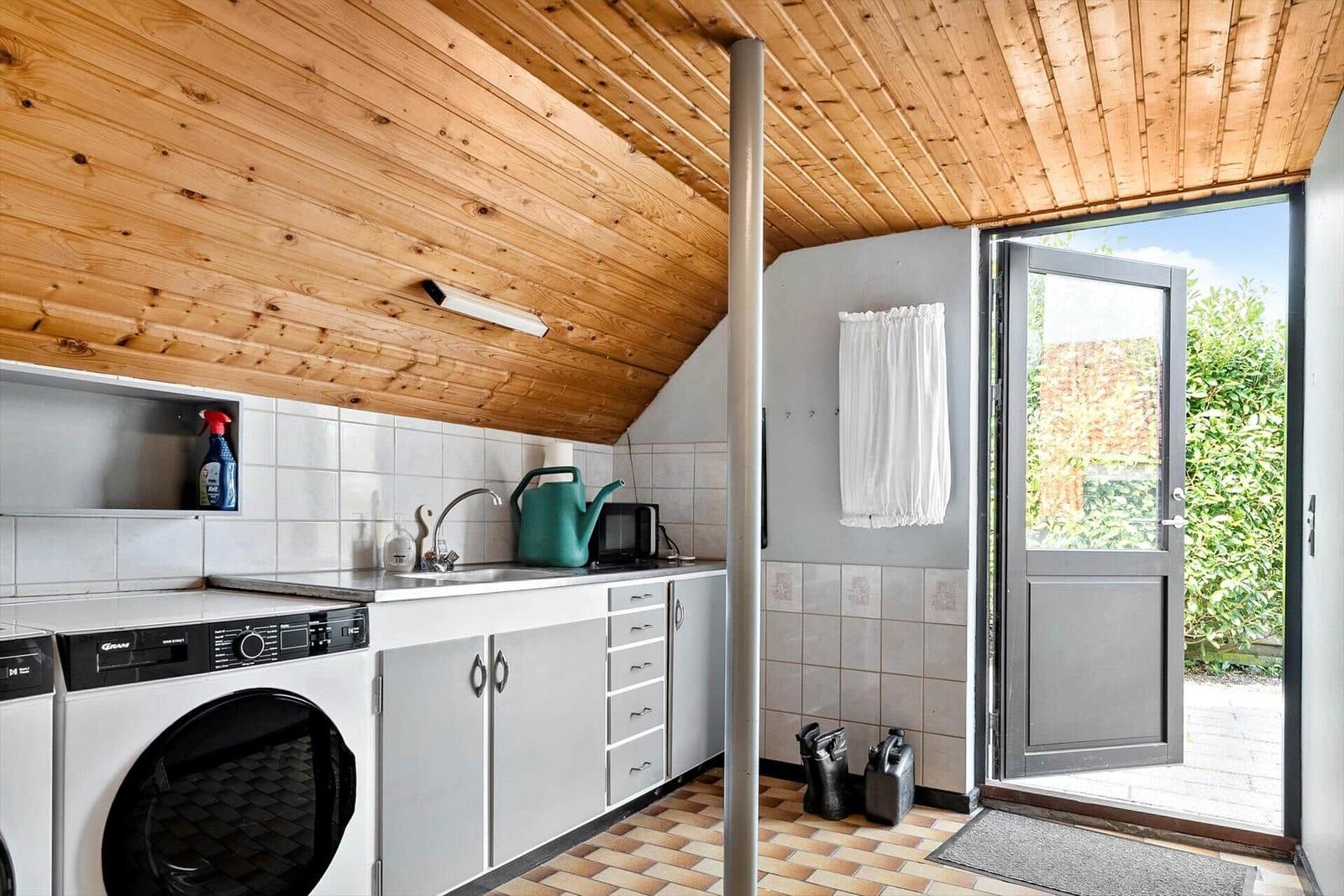 Küche mit Waschmaschine, Spüle und Tür zum Garten.