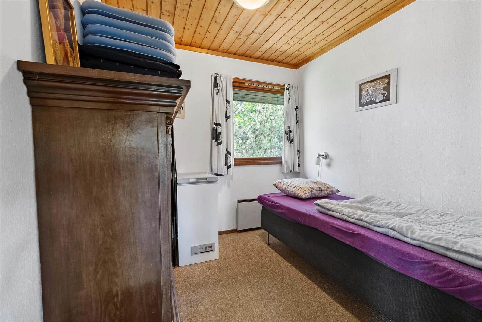 Ein Schlafzimmer mit Bett, Schrank, Fenster und Klimagerät.