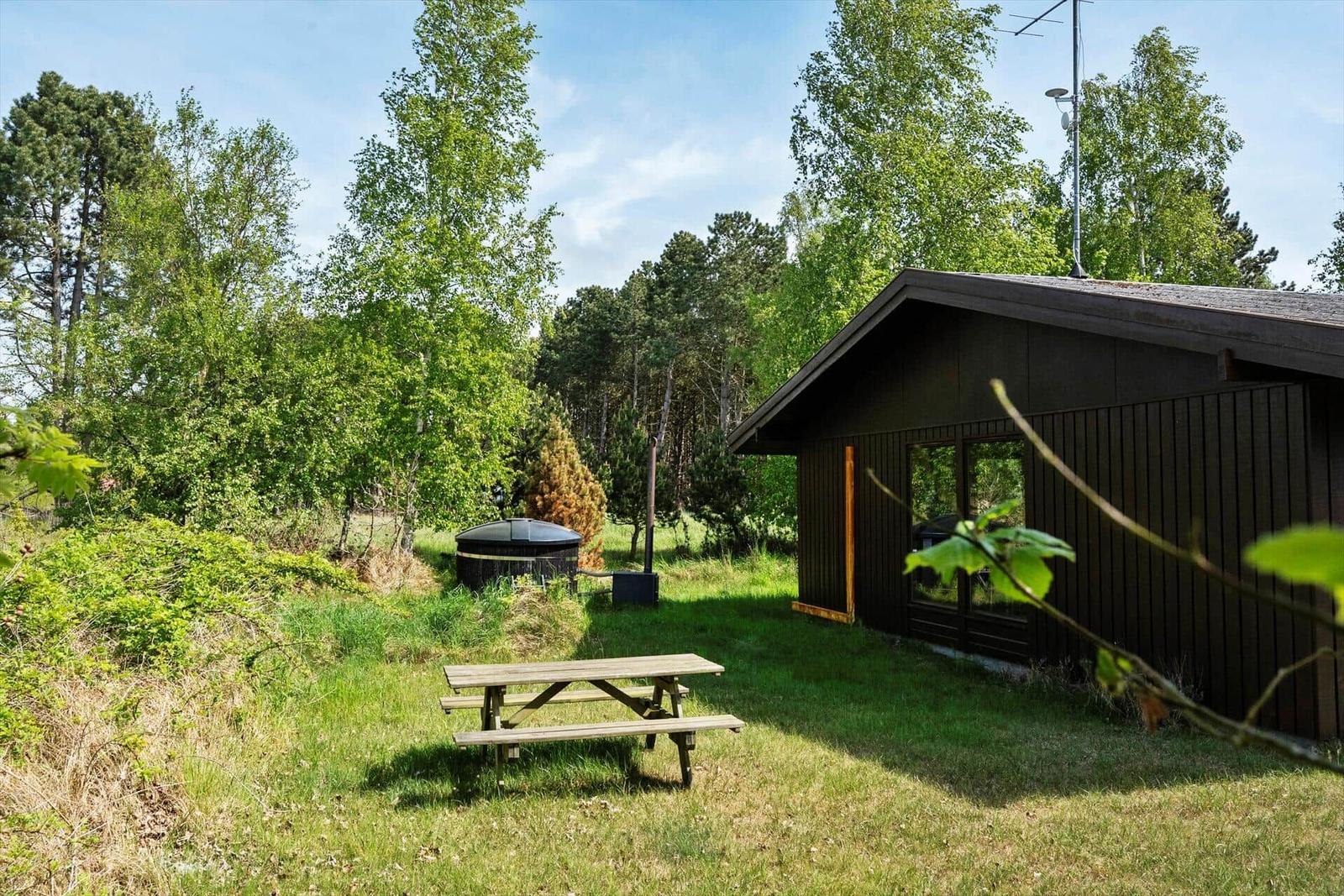 Holzhütte mit Grillplatz und Picknicktisch im Grünen.