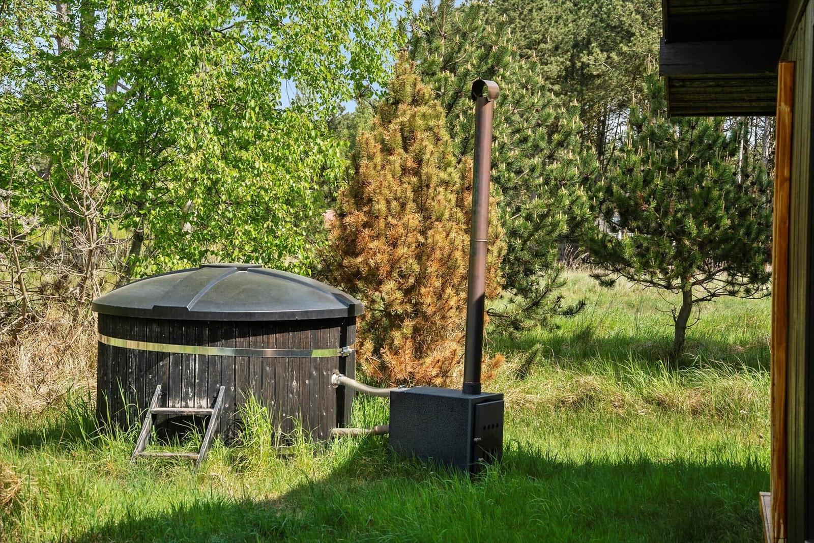Außenwhirlpool mit Holzbecken und Heizung im Grünbereich.