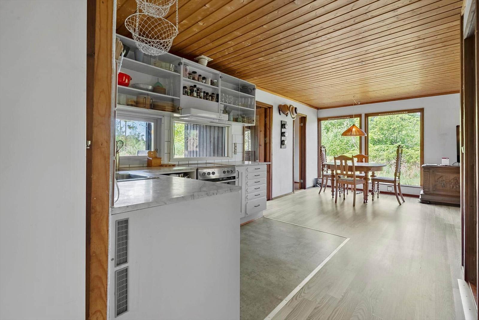 Küche mit Essbereich und Holzdecke. Tisch mit Stühlen und Fenster zur Aussicht.
