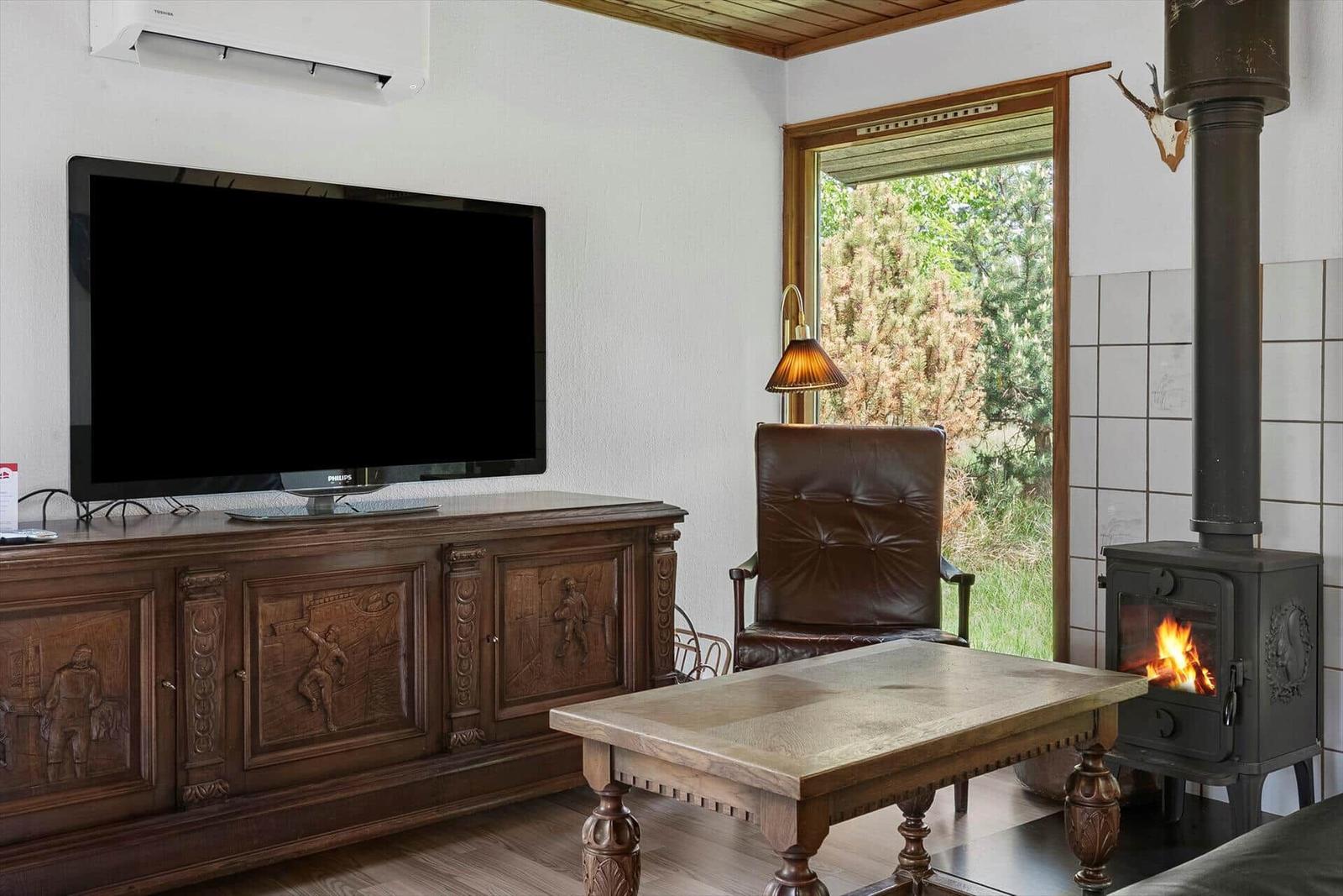 Ein Wohnzimmer mit Kamin, Fernseher und Holzmöbeln.