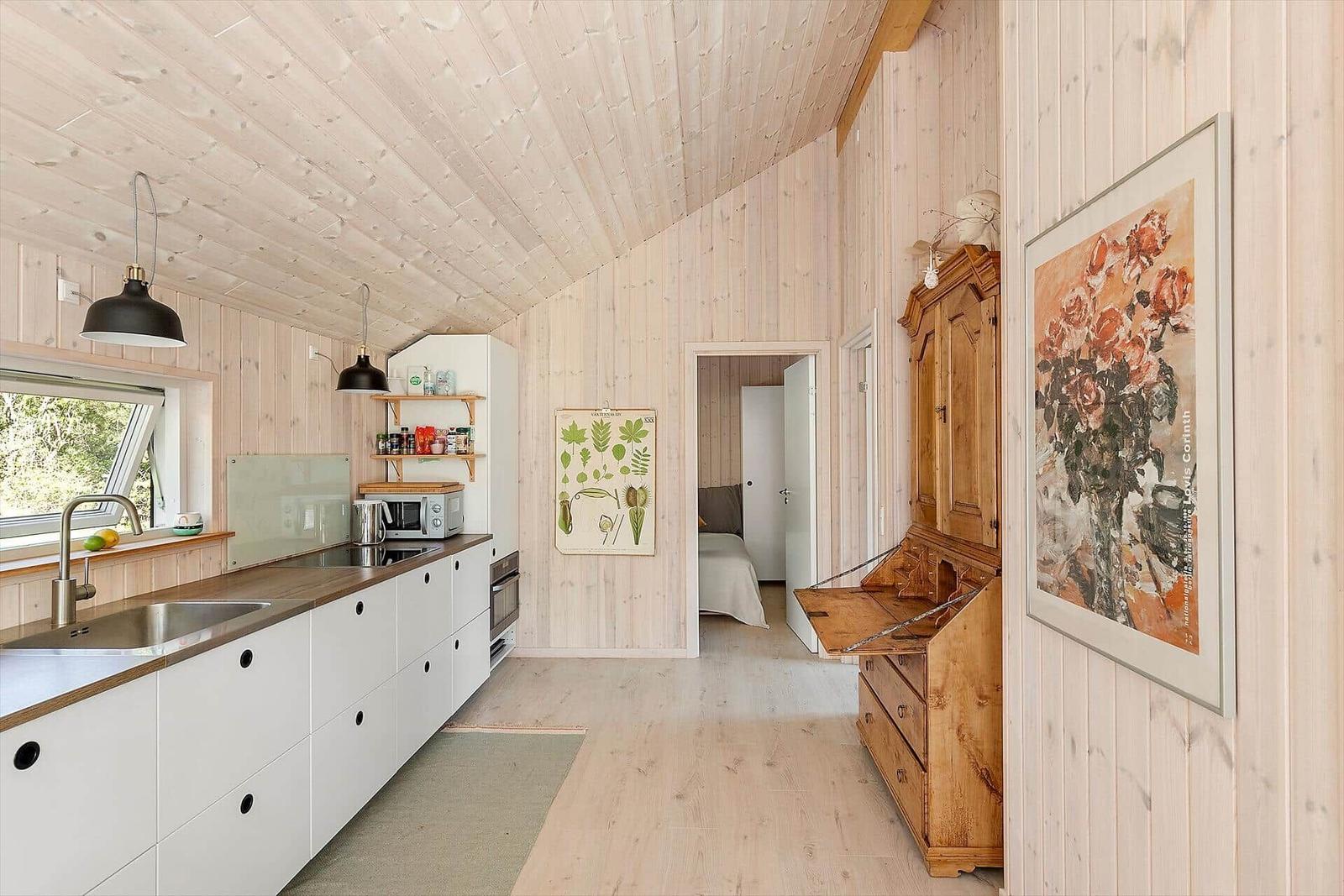 Küche mit Holzwand und Schlafzimmer im Hintergrund.