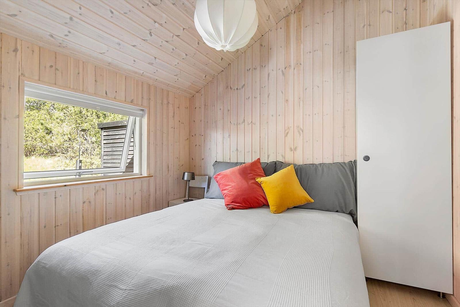 Schlafzimmer mit Holzwand, Bett und Fenster