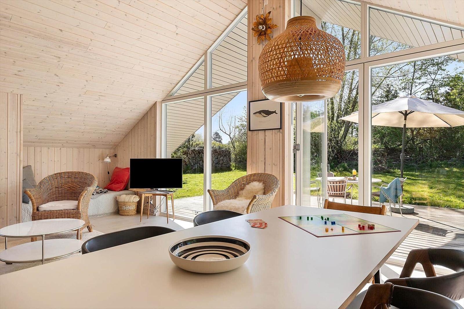 Moderne Wohnküche mit Blick auf den Garten. Esstisch, Sessel und TV sichtbar.