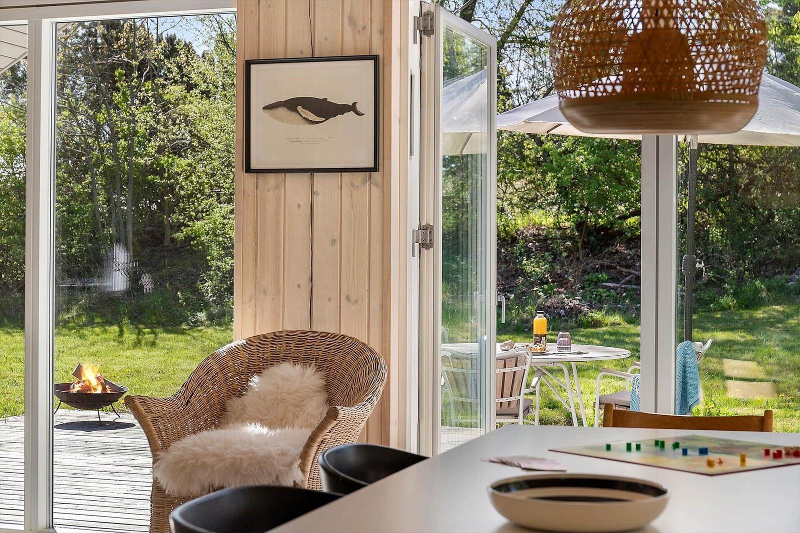Wohnbereich mit Sitzgelegenheit und Blick auf Garten mit Feuerkorb.