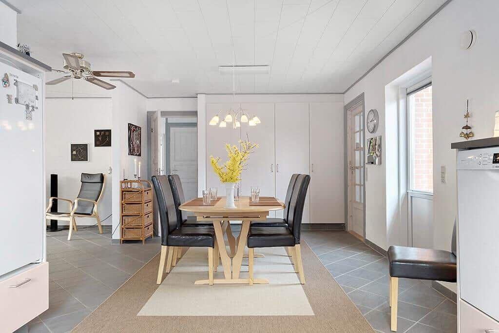 Esszimmer mit Holztisch, schwarzen Stühlen und gelben Blumen.