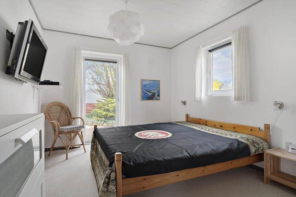 Schlafzimmer mit Bett, Fernseher und Fenster zur Aussicht.