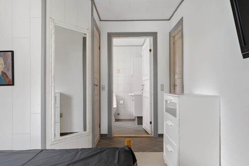 Schlafzimmer mit Spiegel, Kleiderschrank und Blick in das Badezimmer.
