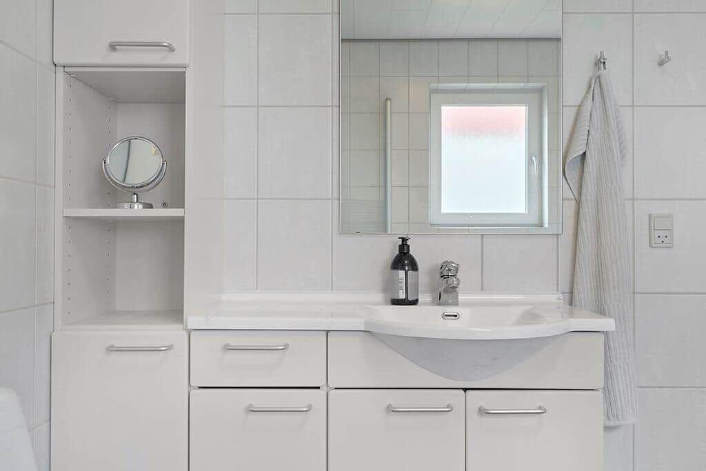 Badezimmer mit Waschbecken, Spiegel und Fenster