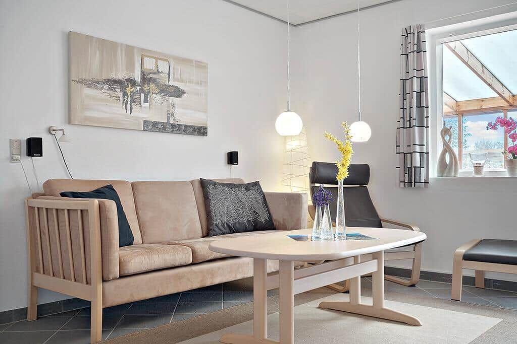 Wohnzimmer mit Sofa, Couchtisch und Sessel. Fenster mit Blick auf Dachgasträume.