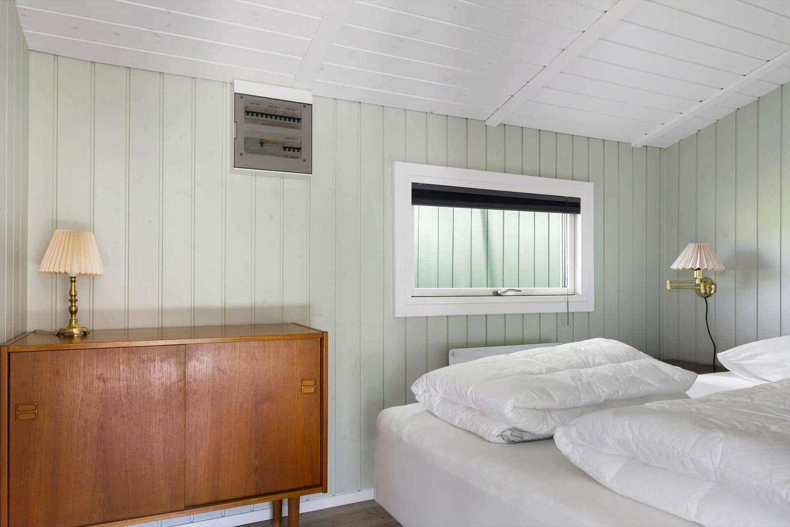 Bedroom with bed, wooden cabinet, and window