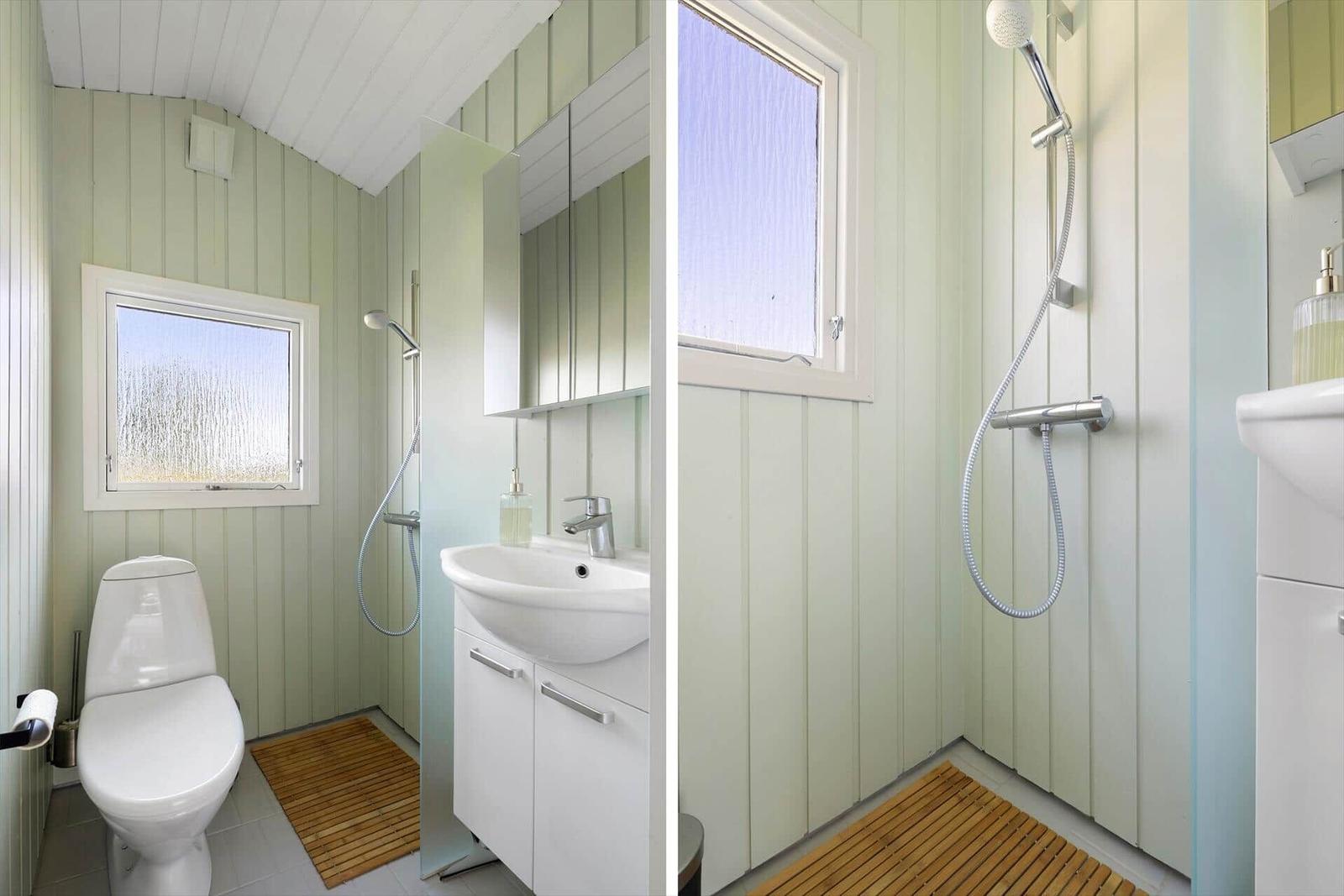 Bathroom with shower, sink and toilet. Wooden floor and green walls.