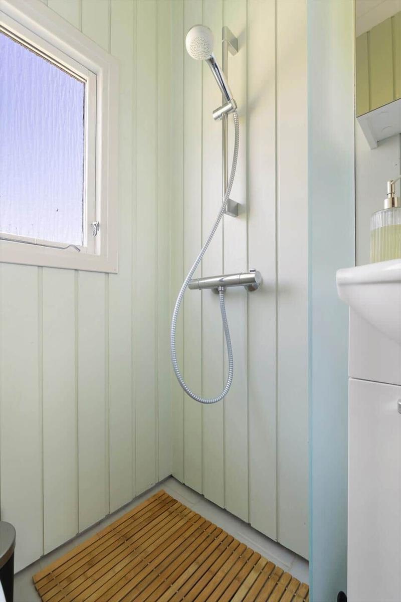 Shower with handheld showerhead, wooden mat, and window