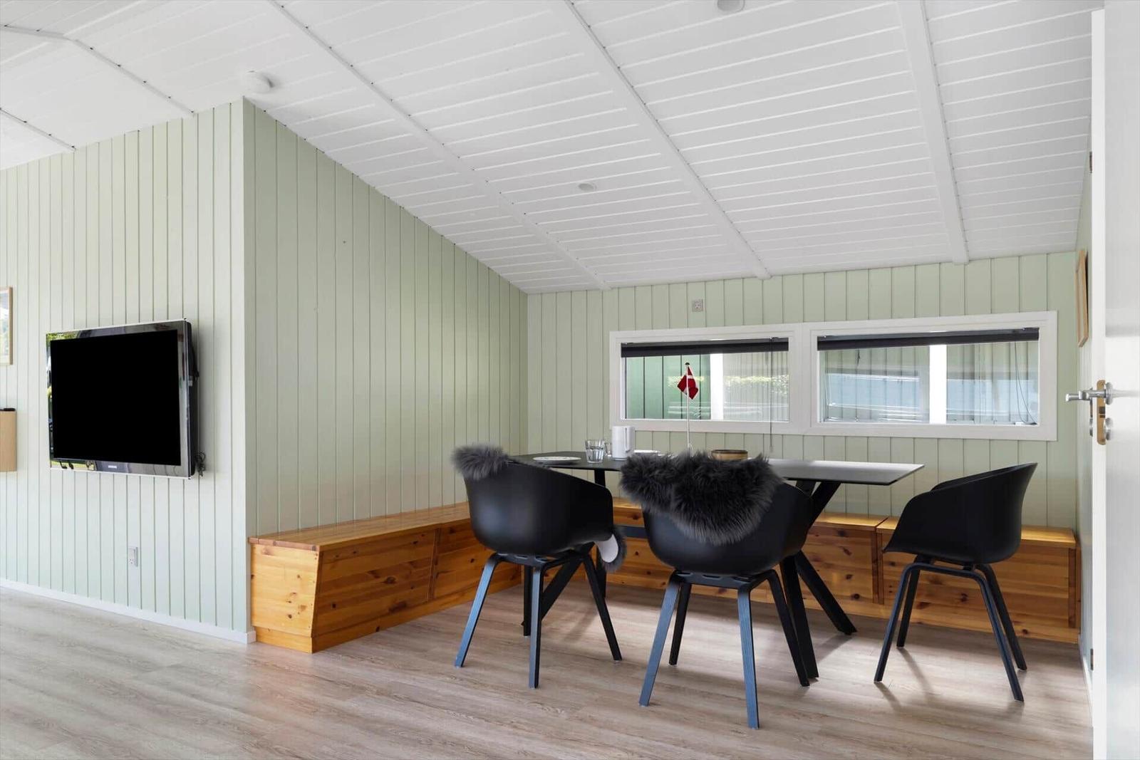 Dining area with table, three chairs, and TV mounted on the wall.