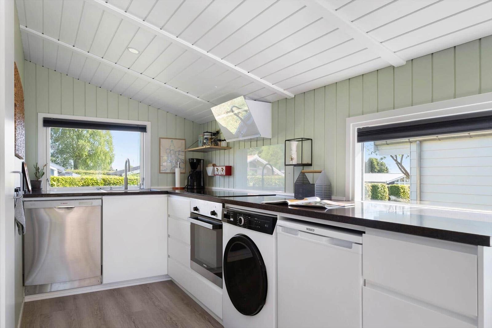 Kitchen with white cabinets, dark countertops, and windows overlooking outside.