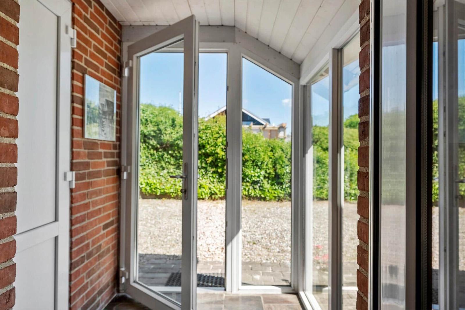Glass door leads to a paved courtyard with green hedges.