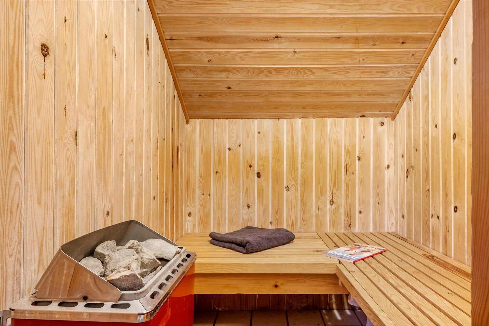 Sauna with wooden walls, bench, stones, and towel.