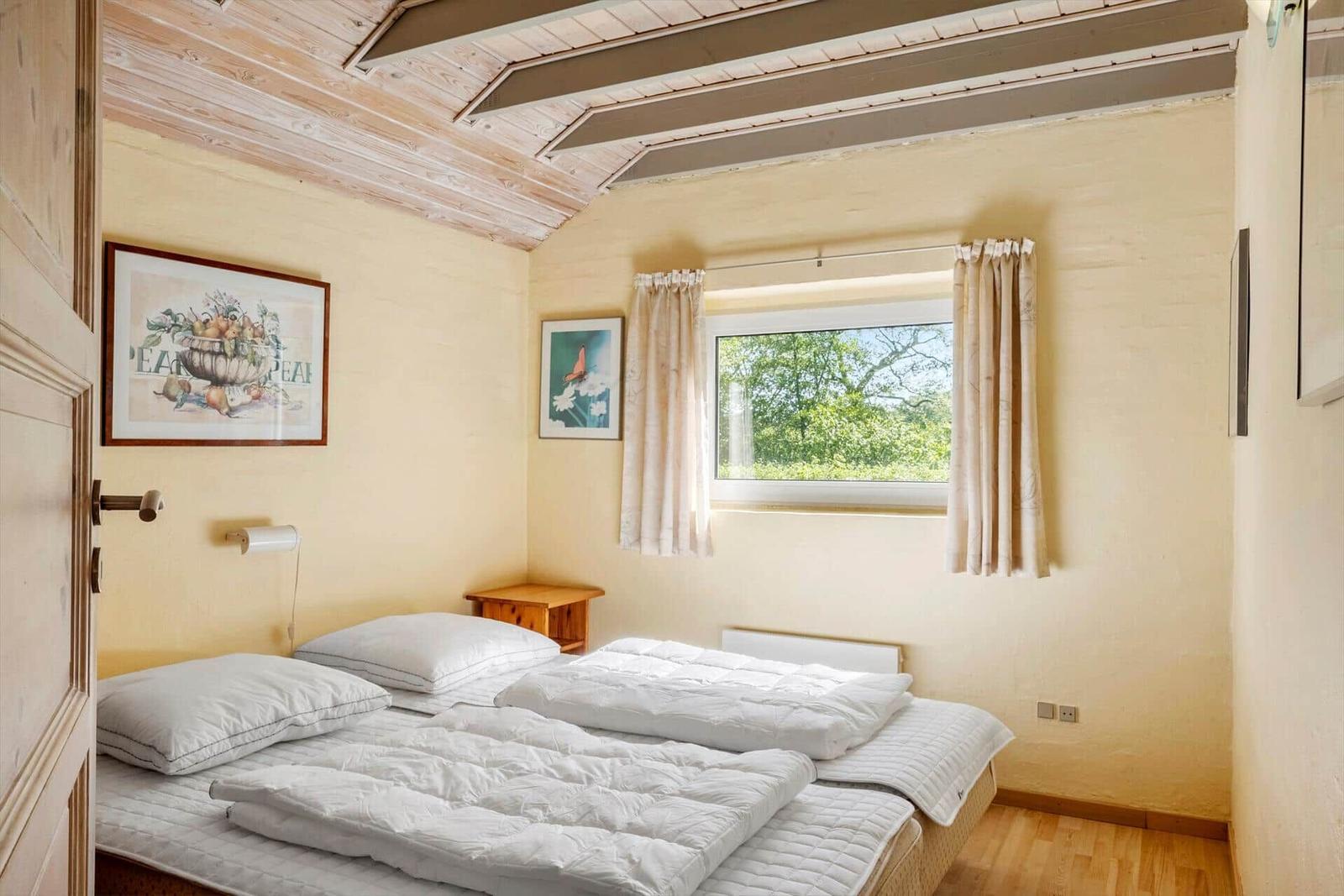 Bedroom with double bed, window, and wooden ceiling.