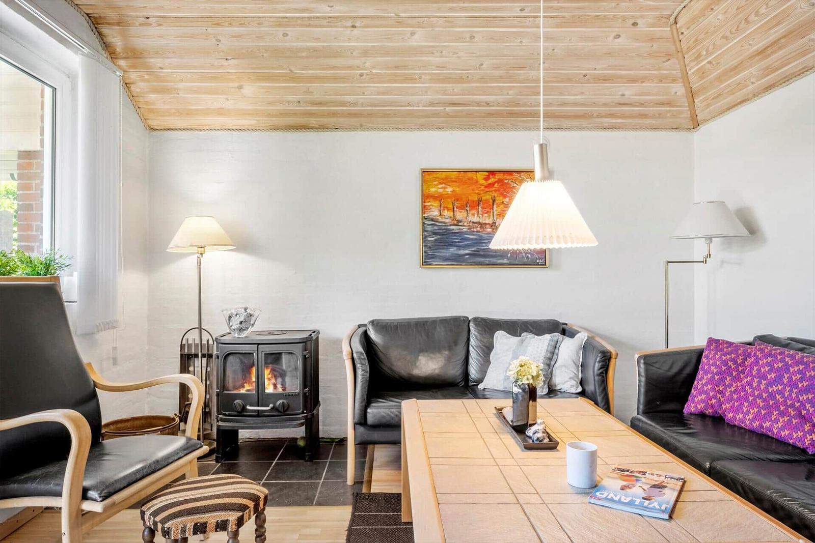 Living room with wooden ceiling, sofa, fireplace, and table.