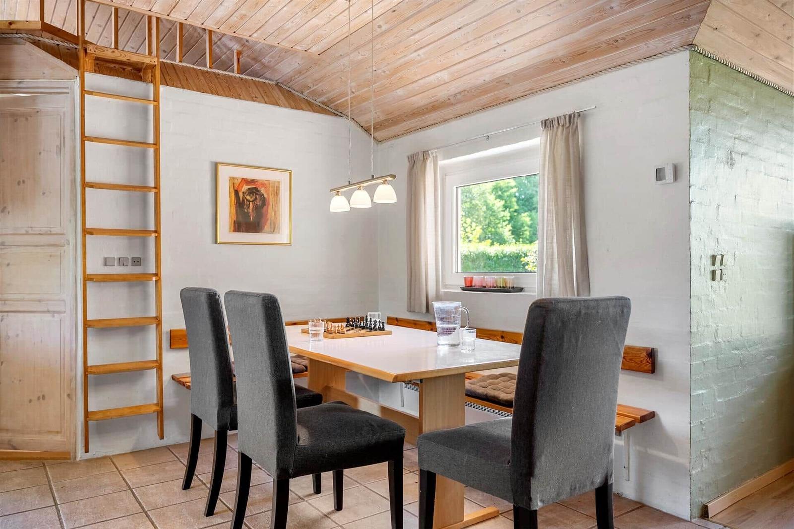 Dining room with table, chairs, and window. Wooden ceiling and ladder to upper level.