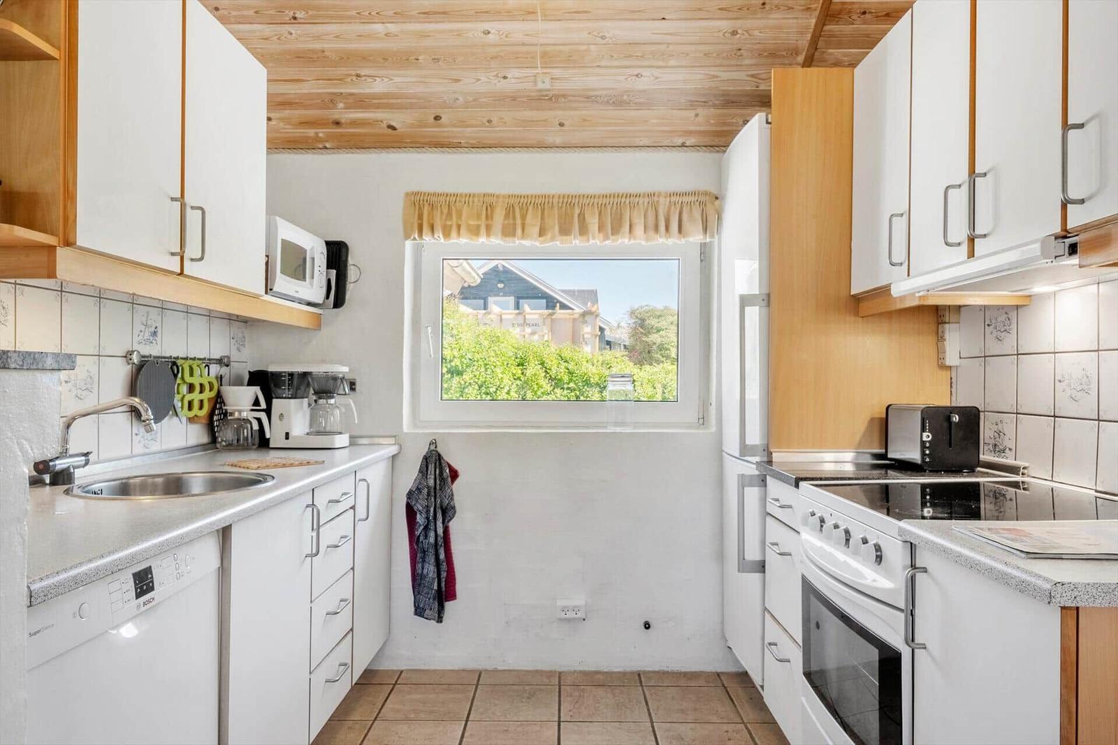 Kitchen with white cabinets, window, and appliances.