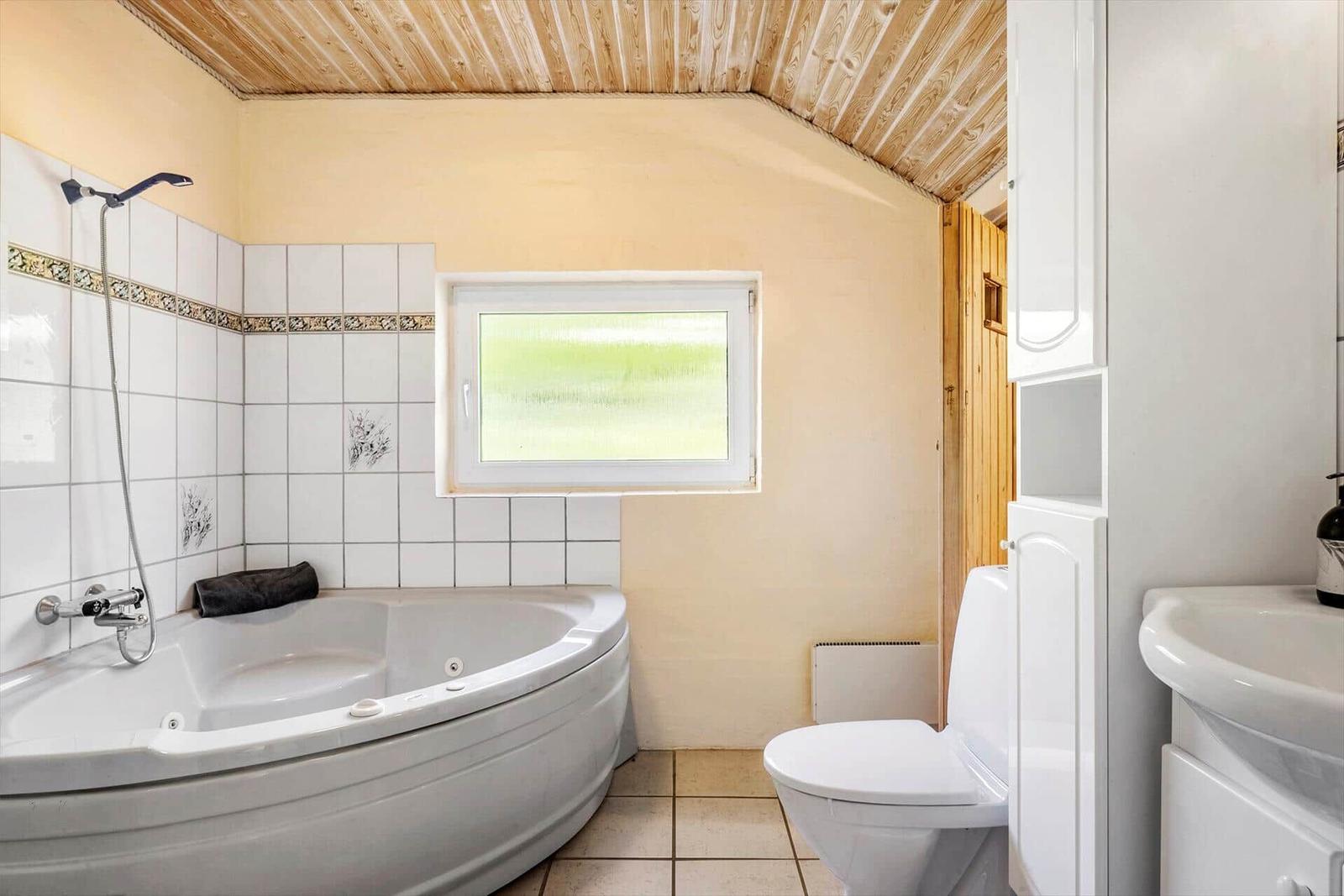 Bath with bathtub, toilet, and sink. Wooden ceiling and frosted glass window.