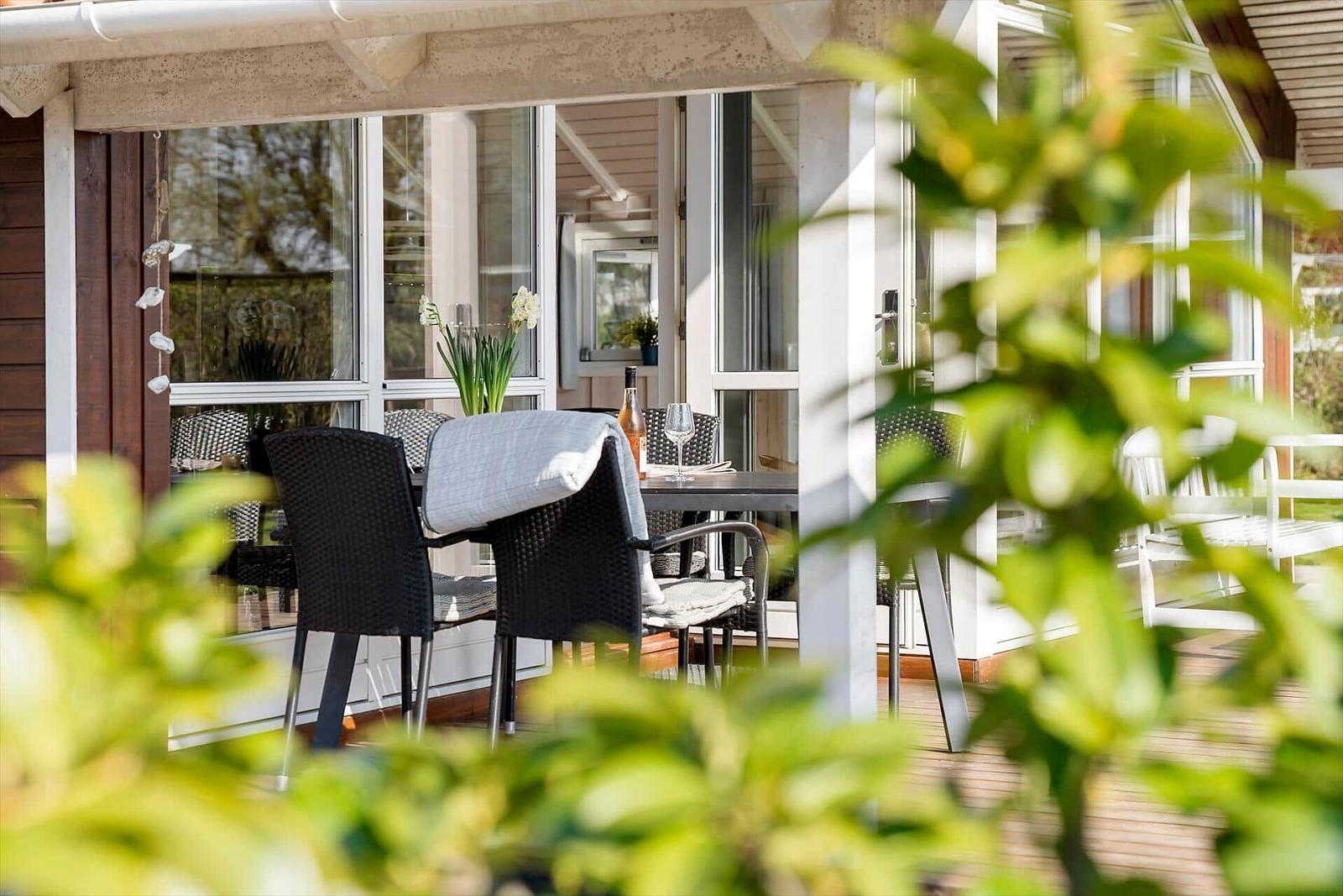 Terrace with table and chairs, view into the house through windows.