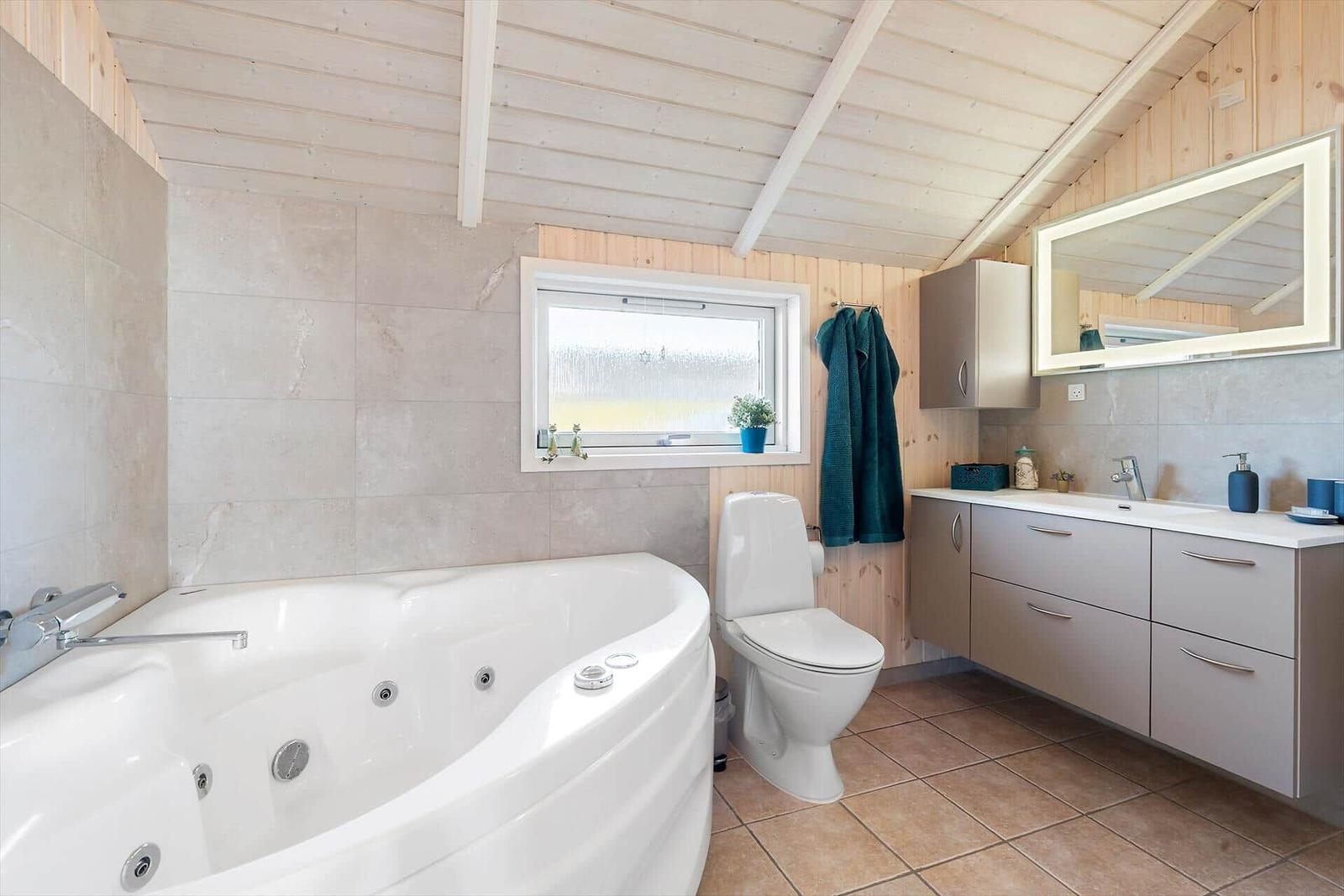 Bathroom with whirlpool, toilet, and sink with mirror.