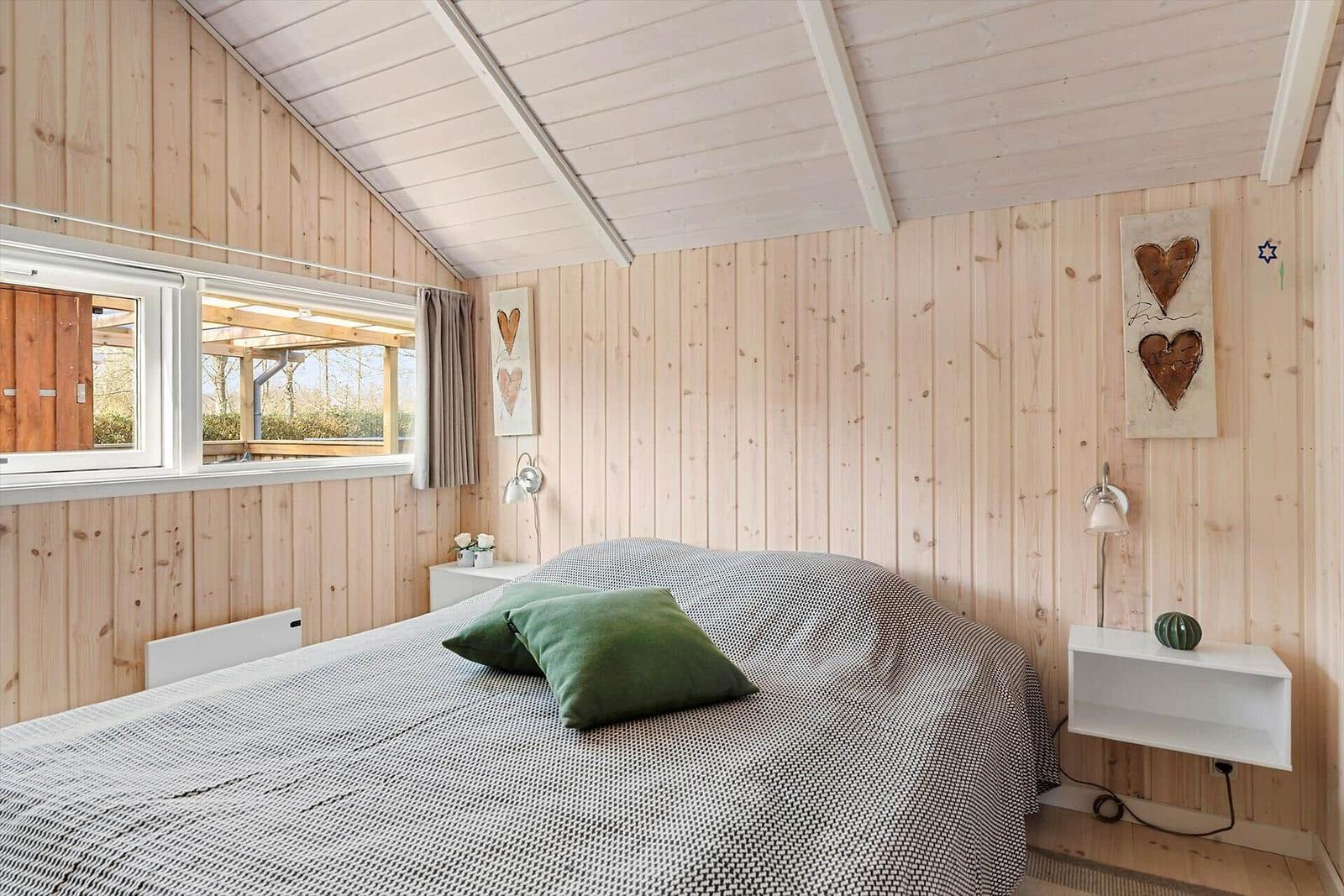 Bedroom with wooden walls, bed, and window to terrace.