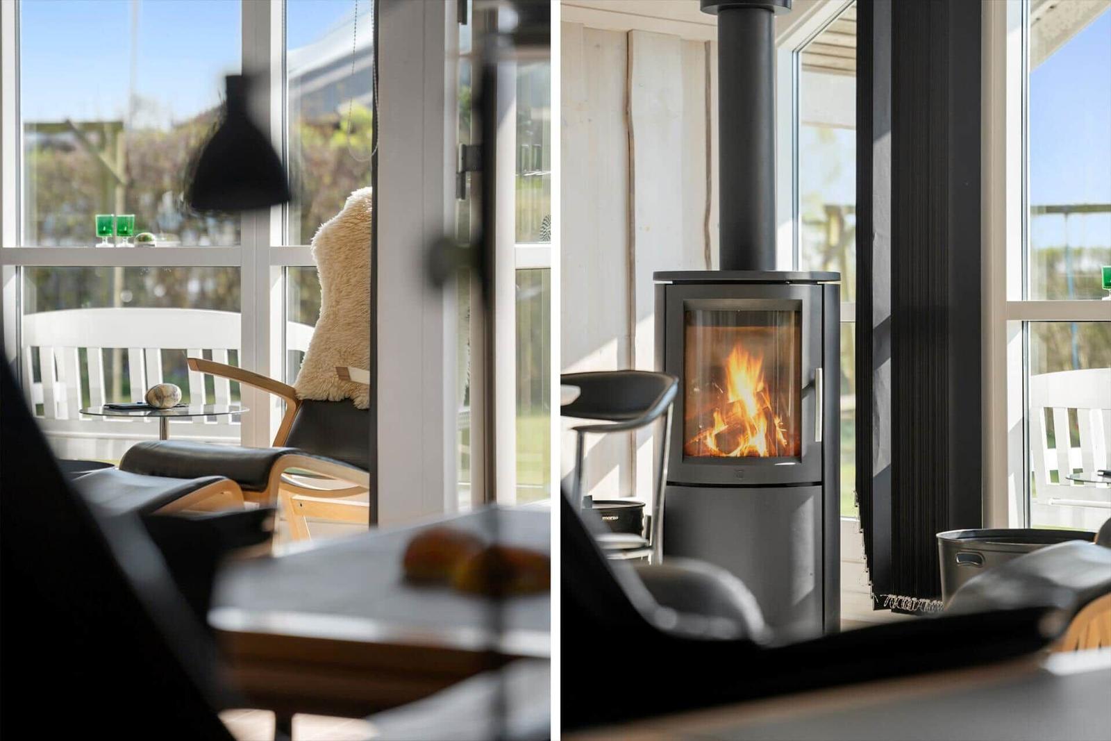A fireplace with burning wood and a seating area with a view of the terrace.