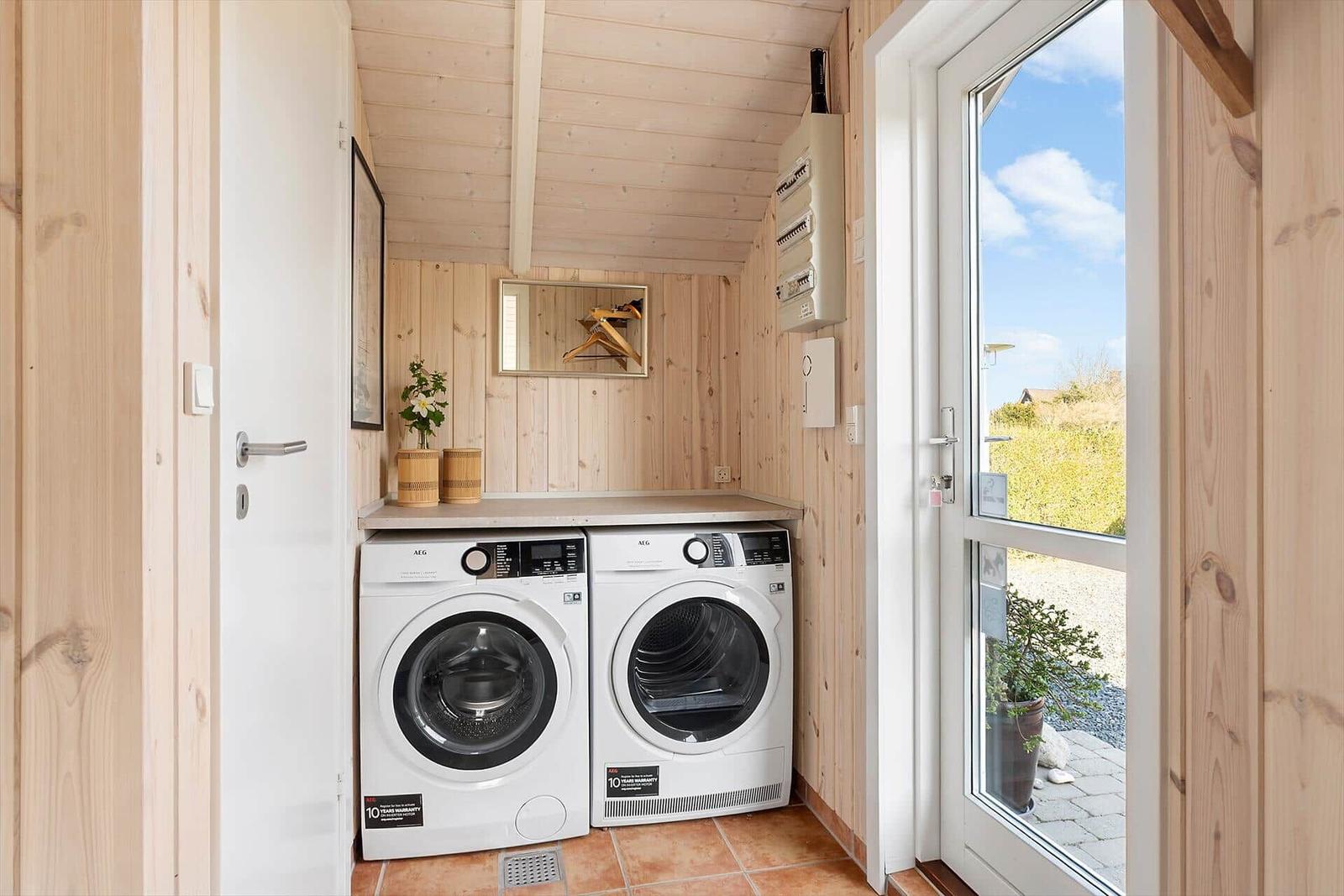 Washing and drying area with wooden walls and window to outdoor terrace.