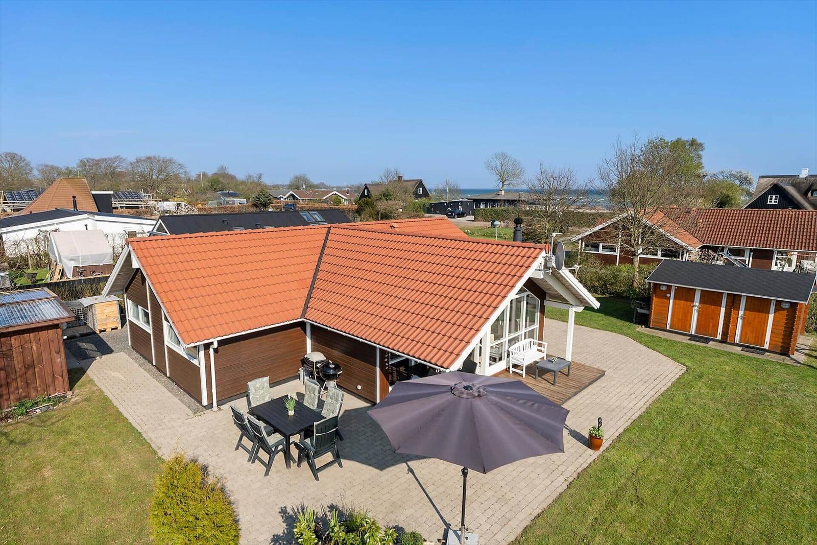 House with terrace, grill, and umbrella. Lawn and view of the water.