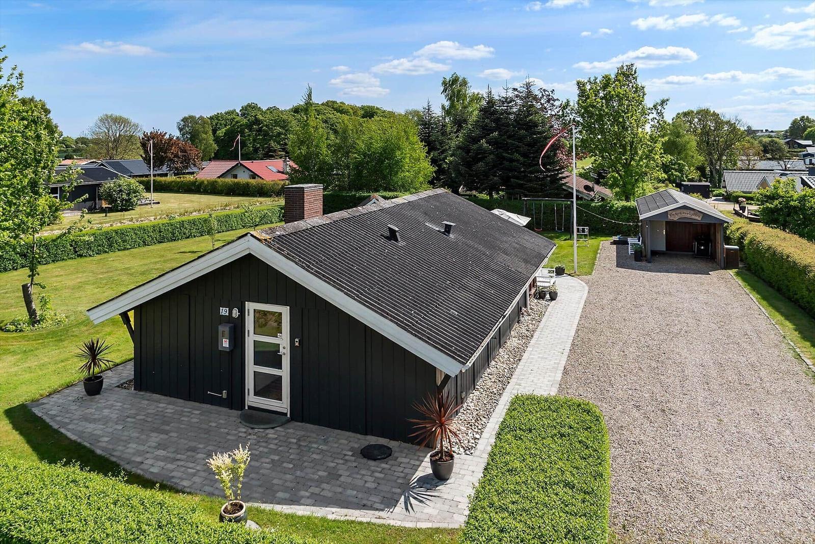 Schwarzes Haus mit Dach, Eingang und gepflastertem Vorgarten.