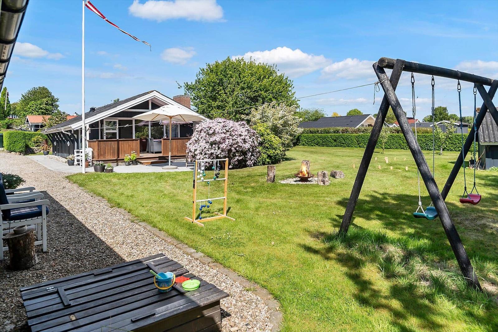 Hinterhof mit Schaukel, Grill und Spielplatz. Haus mit Terrasse und Flagge.