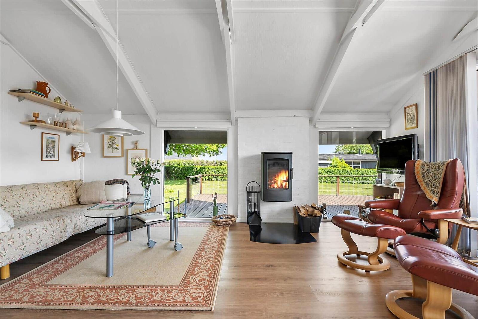 Wohnzimmer mit Kamin, Sofa, Sessel und Terrasse